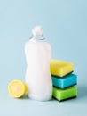 White dishwashing liquid in a plastic bottle, lemon and three foam sponges. Purity and household chemicals. Kitchen detergent on a Royalty Free Stock Photo