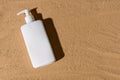 White dispenser with black hard shadow on the sand. Place for text.