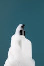 A white dispenser with a cosmetic product in foam on the shelf. Shower gel