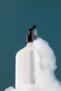 A white dispenser with a cosmetic product in foam on the shelf. Shower gel