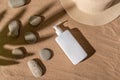White dispenser and stone shadow on stones. Sun hat on the sand. Royalty Free Stock Photo