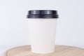 A white disposable coffee cup with a black lid, on a plain white background, concept of coffee breaks, convenience, and Royalty Free Stock Photo