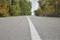 White dividing strip on the asphalt road in the autumn forest Royalty Free Stock Photo