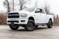 White Dodge Ram 2500 truck parked on a concrete surface in a natural setting.