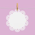 White doily hanging on rope with wooden clothespin