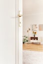 White door in bright living room interior with sunflowers on cupboard on wooden floor. Real photo Royalty Free Stock Photo