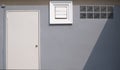 White door, square ventilation shutter and glass blocks with sunlight and shade on surface of gray cement wall Royalty Free Stock Photo