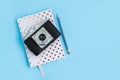 White dotted notebook, pecil and retro camera on blue background with copy space