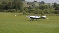 White double-seat propeller-driven PS-28 Cruiser airplane takes off on grass landing strip in co