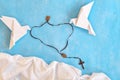 White dove origami carrying rosary or scapular in sky blue background.