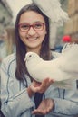 A white dove sits on the head of a laughing girl.