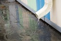 White drainpipe with flooded pavement. Rain water flowing from drain pipe closeup