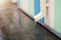 White drainpipe with flooded pavement. Rain water flowing from drain pipe closeup