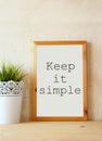White drawing board with the phrase keep it simple written on it against textured wall Royalty Free Stock Photo