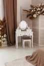 White dressing table with oval mirror and chair is part of cosy interior of beautiful bedroom