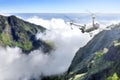 White drone with camera flying above the top of mountain with cloudscapes