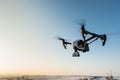 White drone with digital camera flying on sky background