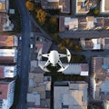White drone flying under civil buildings. Spy digital vehicle quadcopter flying under city. Military technology