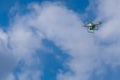 White drone with a green camera flying against the sky. Royalty Free Stock Photo