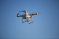 White drone hovering in a bright blue sky