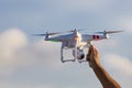 White drone hovering in a bright blue sky with hand ready to cat