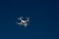 White drone quad copter with flying in the blue sky