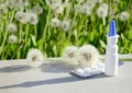 White dropper bottle mock up, blister with medical pills , dandelions on gray background with shadows. Concept of allergy