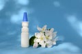 White dropper bottle and spring flowers on blue background with shadows with copy space. Concept of allergy treatment, medicines Royalty Free Stock Photo