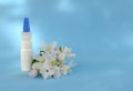 White dropper bottle and spring flowers on blue background with shadows with copy space. Concept of allergy treatment, medicines Royalty Free Stock Photo