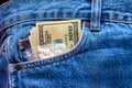 White drug pills and US dollar banknotes in the pocket of jeans. Concept of med expenses or illegal drug distribution. Royalty Free Stock Photo
