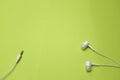 White ear buds or earphones on a green background