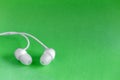 White earbuds on green colorful background Royalty Free Stock Photo