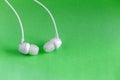 White earbuds on green colorful background Royalty Free Stock Photo