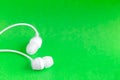 White earbuds on green colorful background Royalty Free Stock Photo