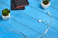 White earphones, two black notebooks and green succulents in pots on blue wooden tabletop or background. Close up, copy Royalty Free Stock Photo