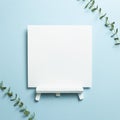 White easel blank canvas with eucalyptus leaves isolated on blue background Royalty Free Stock Photo