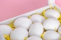 White Easter eggs in wooden box on pink background. Selective focus. Festive greeting card banner. Copy space. Close-up Royalty Free Stock Photo