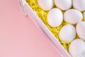 White Easter eggs in wooden box on pink background. Selective focus. Festive greeting card banner. Copy space. Close-up. Royalty Free Stock Photo
