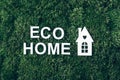 White eco house model on green grass, inscription Eco home over moss backdrop. Top view. Copy space. Banner. Biophilia Royalty Free Stock Photo