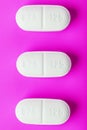 White Ecstasy pills in a row on a pink background, isolate Royalty Free Stock Photo