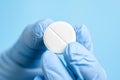 White effervescent or carbon tablet in hand in disposal glove. Doctor, pharmacist or scientist fingers holding pill