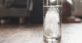 White effervescent tablet in glass with water on table