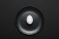 White egg on a black plate on a black background. Concept healthy food, diet. Top view, flat lay Royalty Free Stock Photo