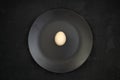 White egg on a black plate on a black background. Concept healthy food, diet. Top view, flat lay. Royalty Free Stock Photo