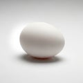 A white egg resting on a plain white surface, casting a soft shadow Royalty Free Stock Photo