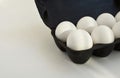 White eggs in a black container on a contrasting white background.
