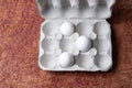 White eggs in a carton box on a brown textured paper background Royalty Free Stock Photo