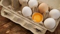 White eggs carton and cracked egg half with yolk top view on wooden background Royalty Free Stock Photo