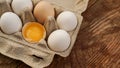 White eggs carton and cracked egg half with yolk top view on wooden background Royalty Free Stock Photo