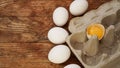 White eggs carton and cracked egg half with yolk top view on wooden background Royalty Free Stock Photo